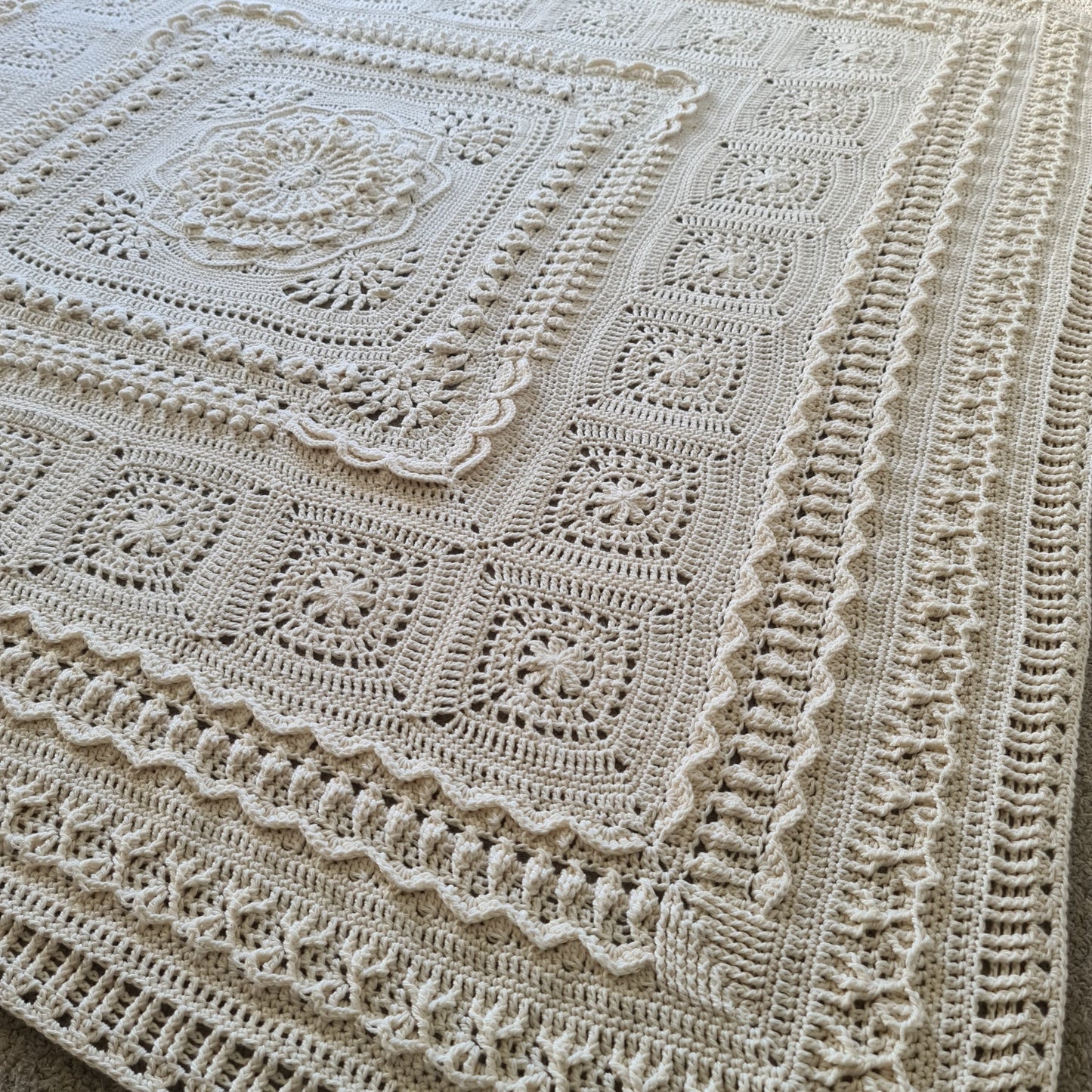 Parchment Nimue blanket lying across a bed.