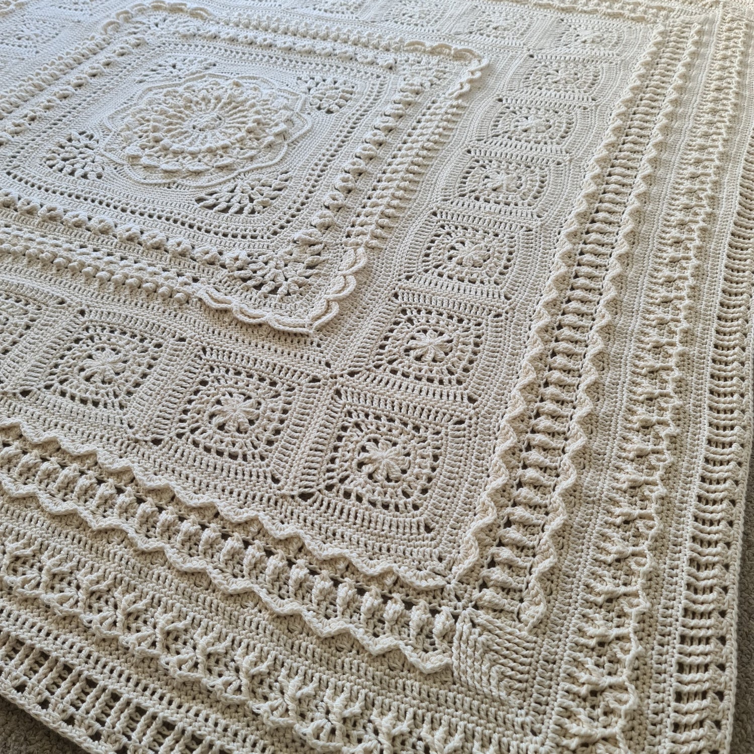 Parchment Nimue blanket lying across a bed.