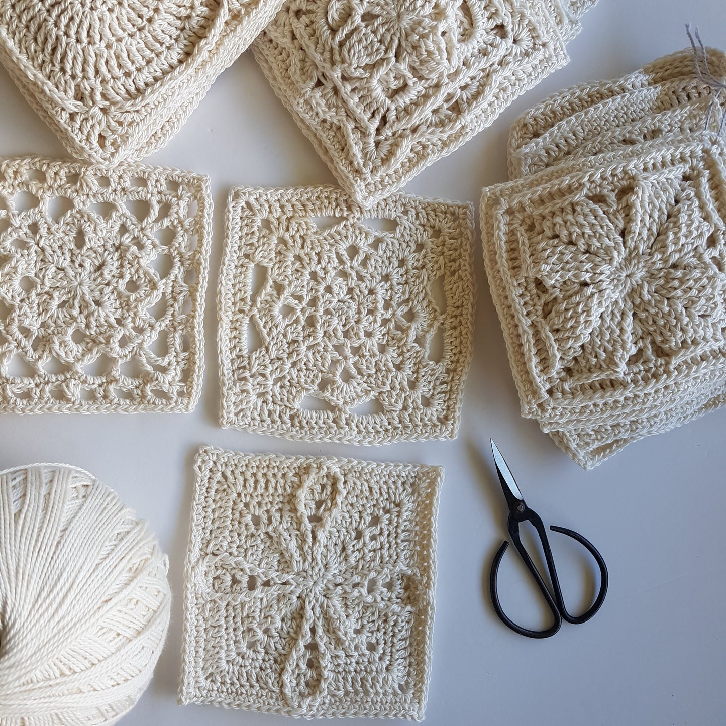 Cream granny squares from Granny Square Flair by Shelley Husband with a ball of yarn and a pair of black yarn scissors