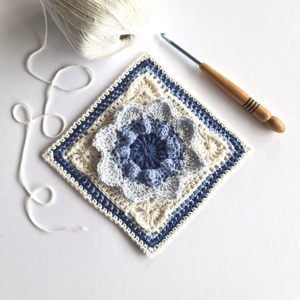 Charlene granny square crochet pattern by Shelley Husband with a ball of yarn and a crochet hook