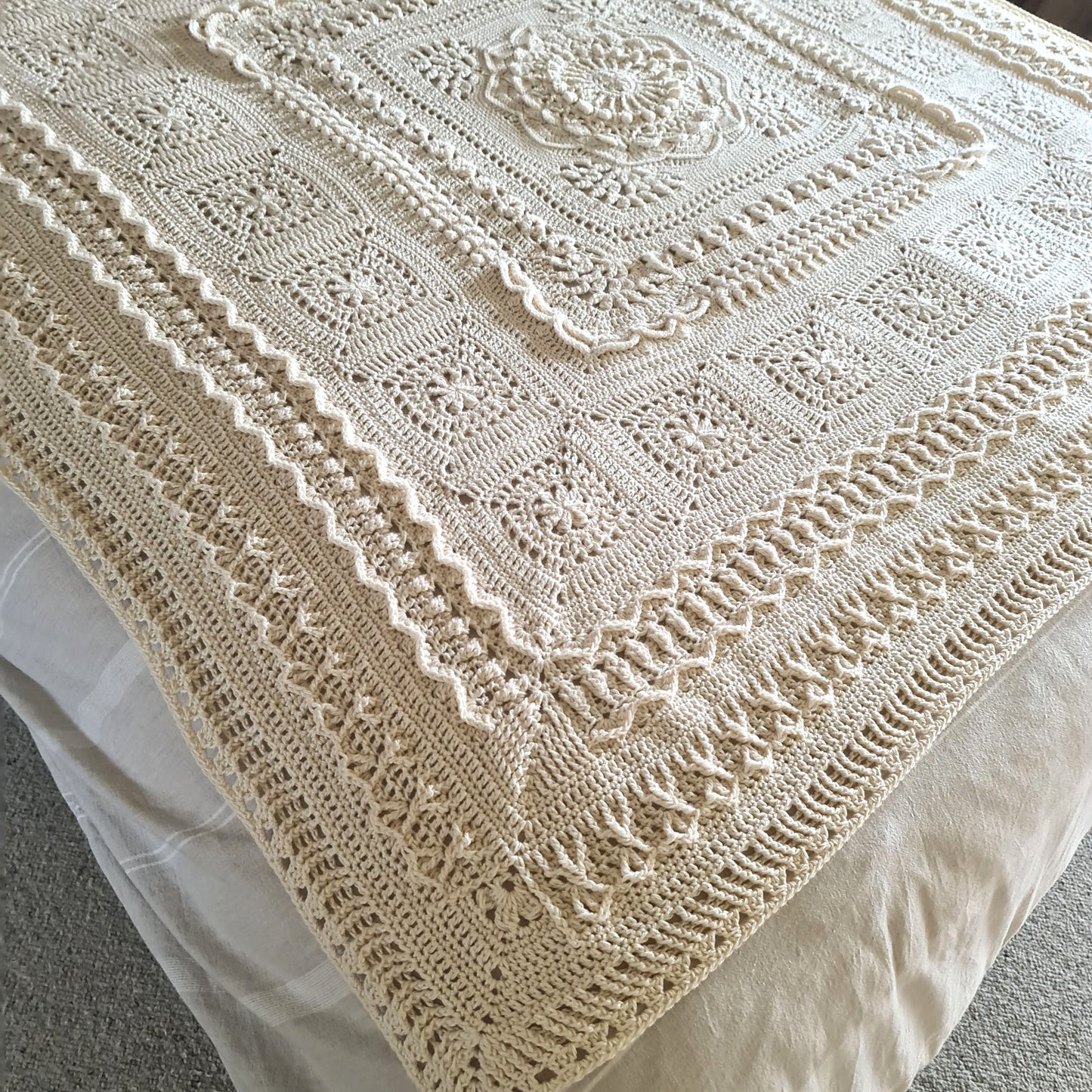 Parchment Nimue blanket lying across a bed.