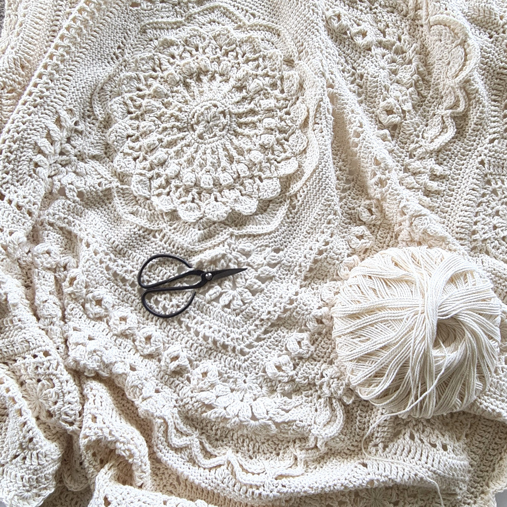 Nimue Crochet Blanket by Shelley Husband with a ball of yarn and a pair of black yarn scissors on top