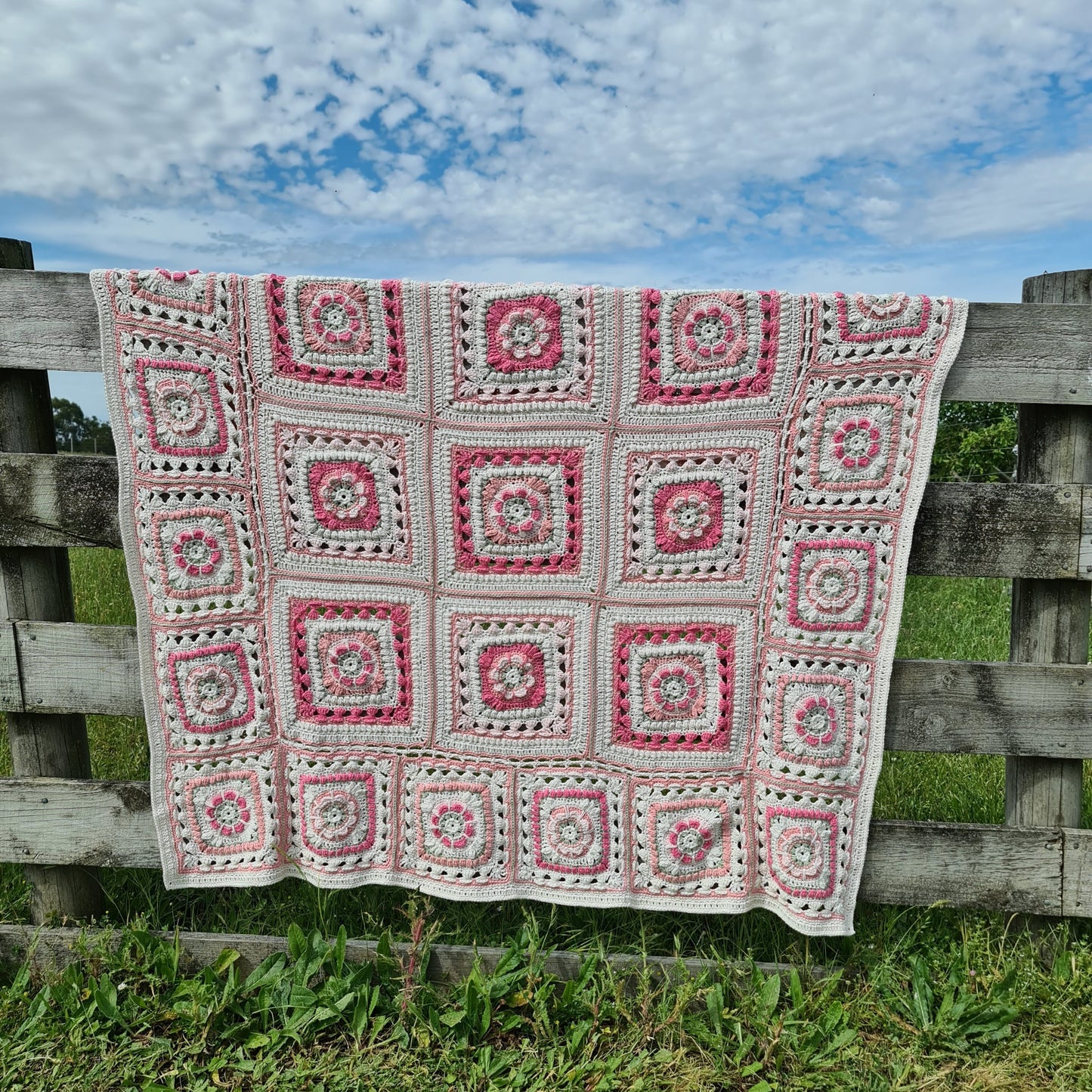 Pink Persnickety Blanket crochet pattern by Shelley Husband hanging over a fence
