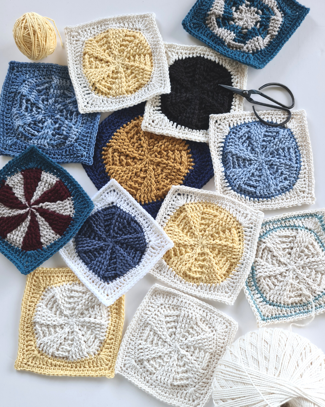 An assortment of Vinyl Revival Granny square crochet patterns by Shelley Husband with balls of yarn and a pair of black yarn scissors
