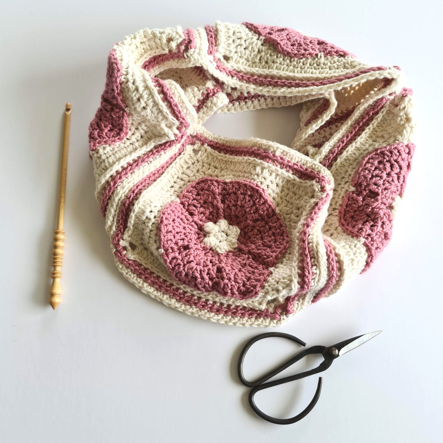 Iris Cowl by Shelley Husband in pink and cream with a wooden crochet hook and a pair of black yarn scissors