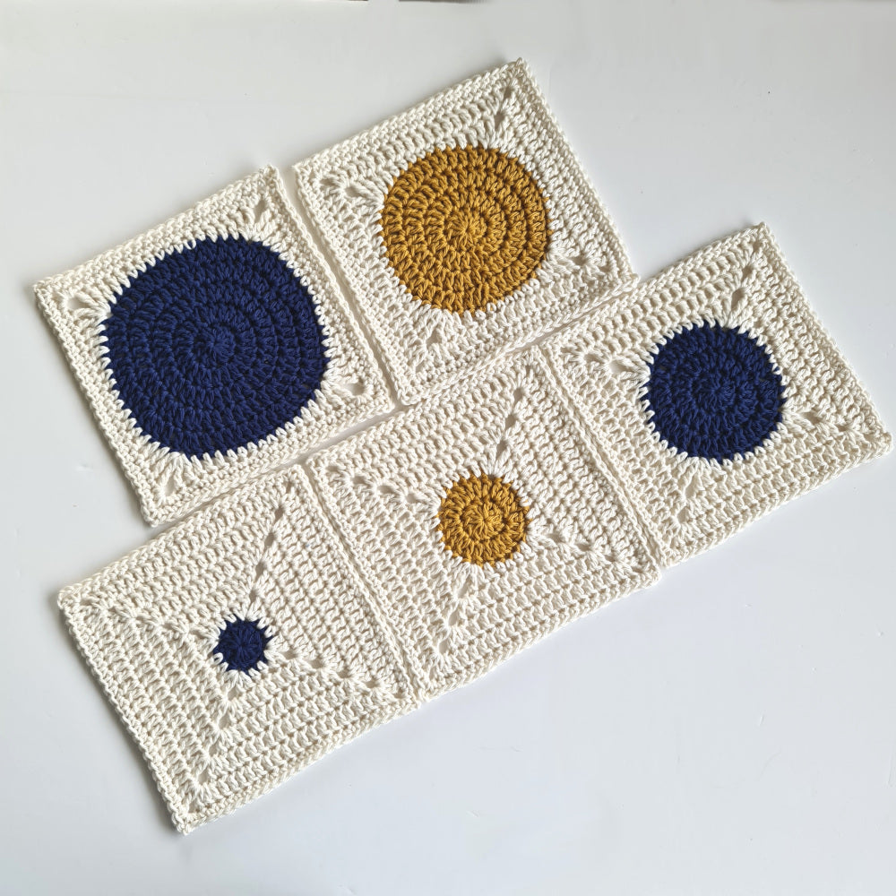 Five granny squares from Dotty Spotty showing the different size circles of each of the five granny squares in the pattern. Top has Navy blue circle, then mustard yellow circle. Lower row has two navy circle designs either side of a mustard yellow circle square.
