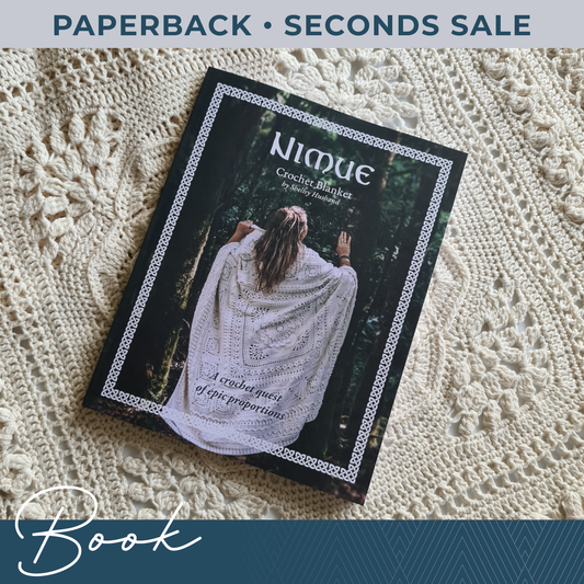 A book called Nimue lies on a crochet blanket. Text on the graphic says 'Paperback - Seconds Sale' and 'Book'