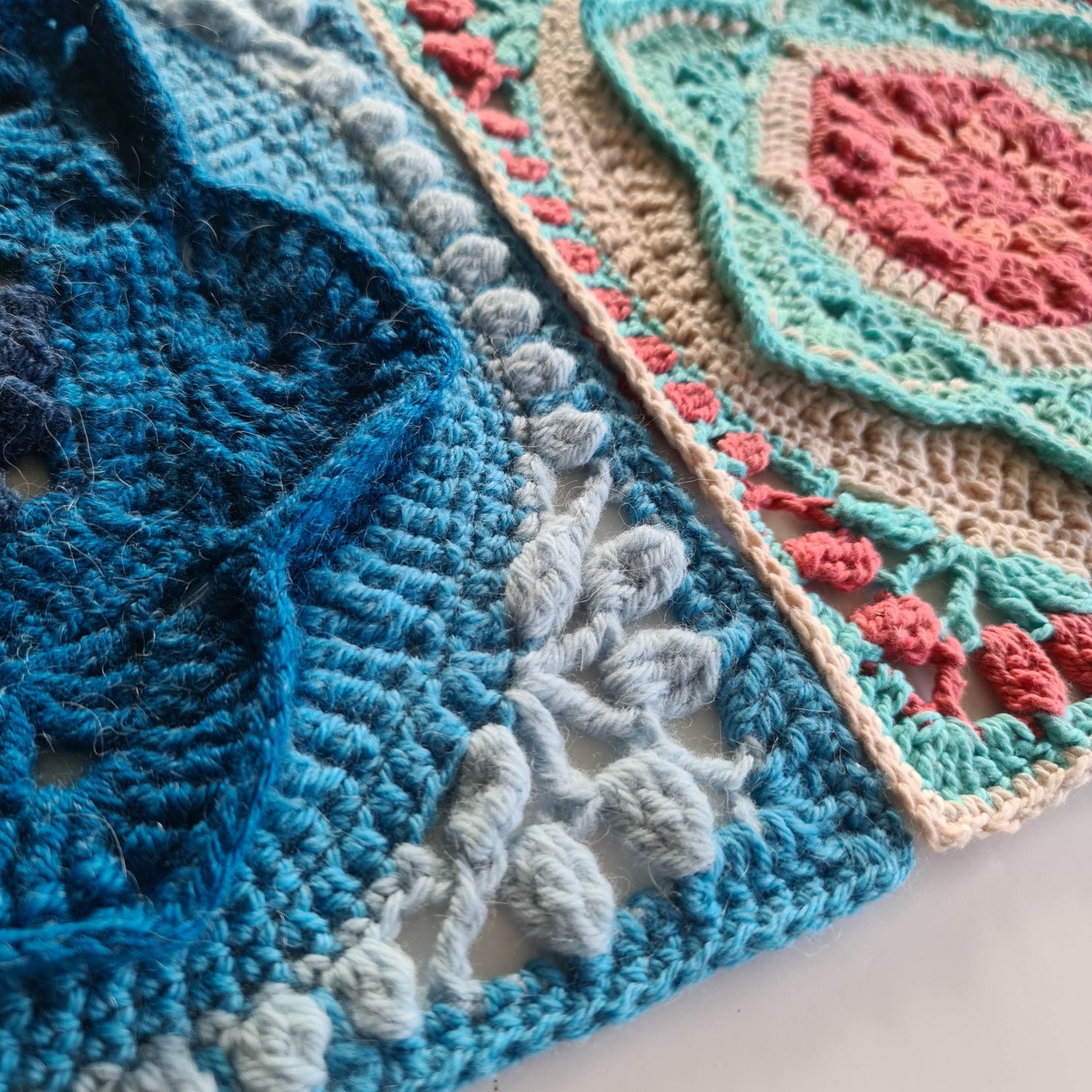 close up view of 2 floral granny squares, one is made with various blues and the other pink, green and cream Asterales Crochet Granny Square Pattern by Shelley Husband