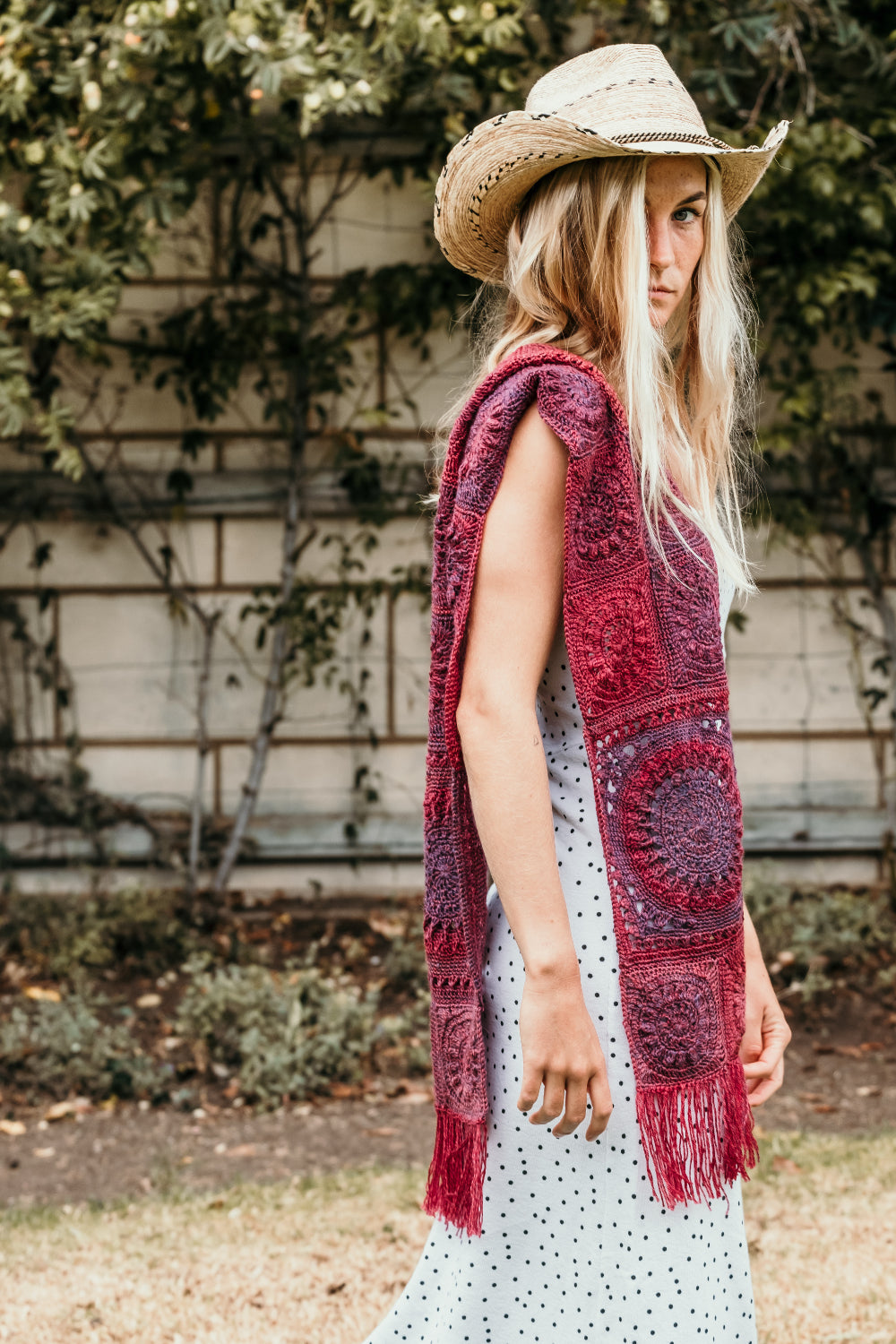 Bloom Cowl and Scarf Project by Shelley Husband Crochet. Blonde woman in cowboy hat wearing the scarf in reds and purples over her shoulder