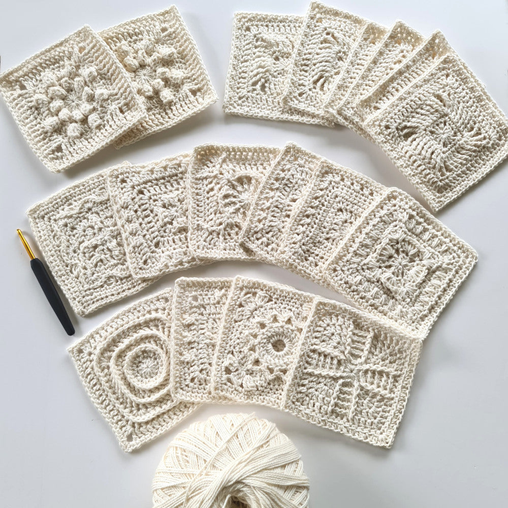 Rows of different parchment granny squares from Granny Square Academy 2 book all laid on a white background. A large ball of parchment yarn sits at the bottom in the middle.