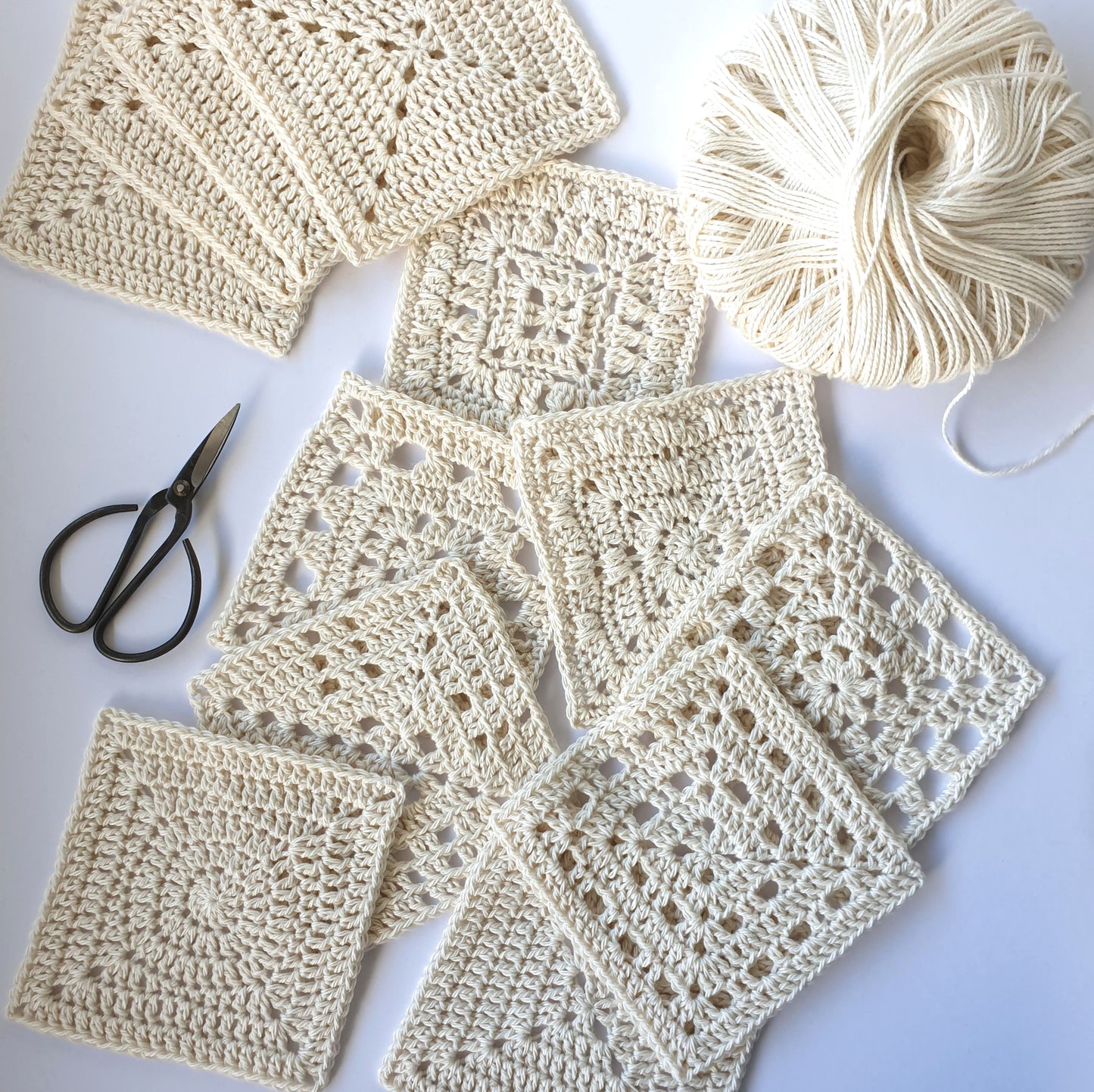 Cream granny squares with a ball of cream yarn and a pair of black yarn scissors from Granny Square Academy book by Shelley Husband