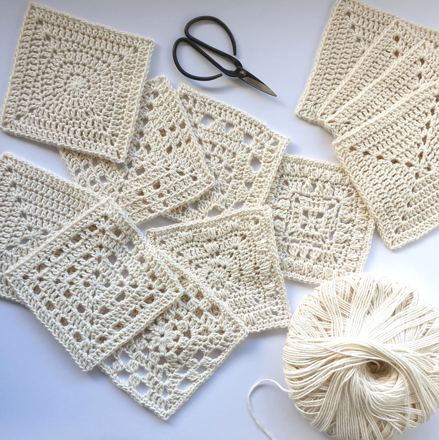 Granny squares from Granny Square Academy 2 with a black handled crochet hook and a pair of gold yarn scissors