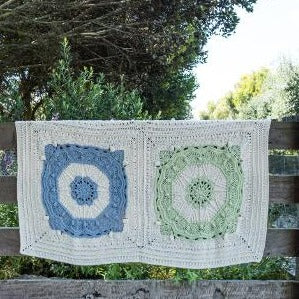 Two colours of Mayan Crochet Blanket Pattern by Shelley Husband hanging over a slatted fence