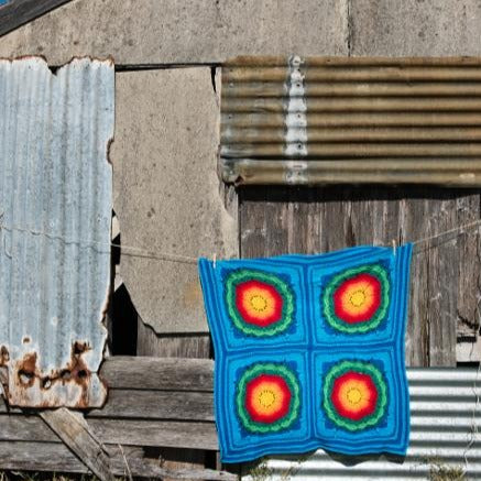 light coloured Mayan Crochet Blanket Pattern by Shelley Husband on a line with a shed behind.