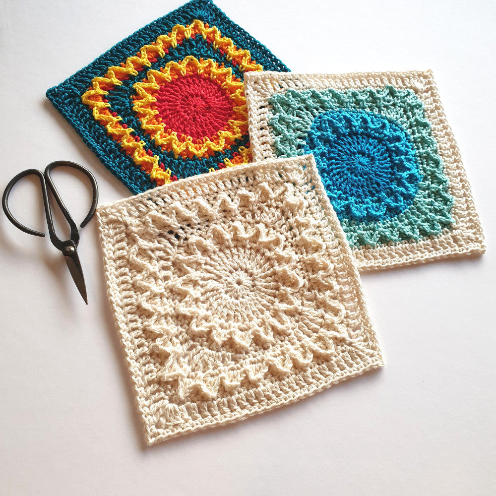 3 Shine with Hope Granny Squares in different colours with a pair of black yarn scissors by Shelley Husband