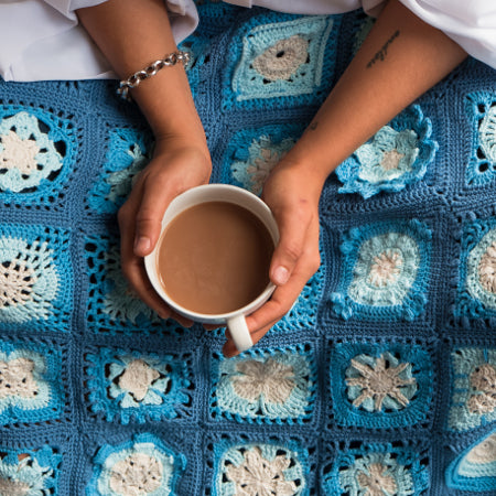 Person holding tea over a blanket from Siren's Atlas by Shelley Husband