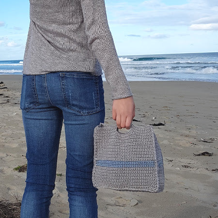 Woman holding Slipstream Project Bag by Shelley Husband on a beach