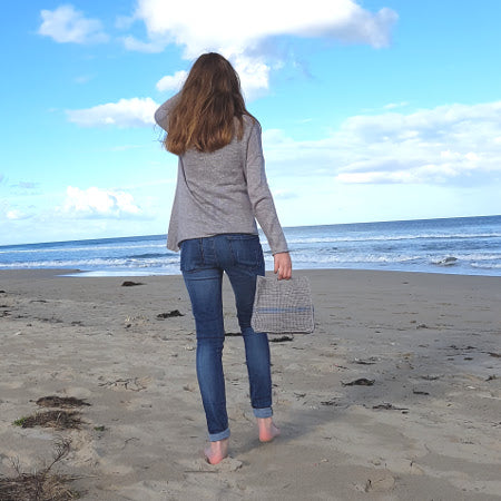 Woman holding Slipstream Project Bag by Shelley Husband on a beach