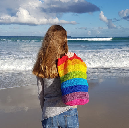 Woman on beach holding Spectrum Project Bag by Shelley Husband over shoulder