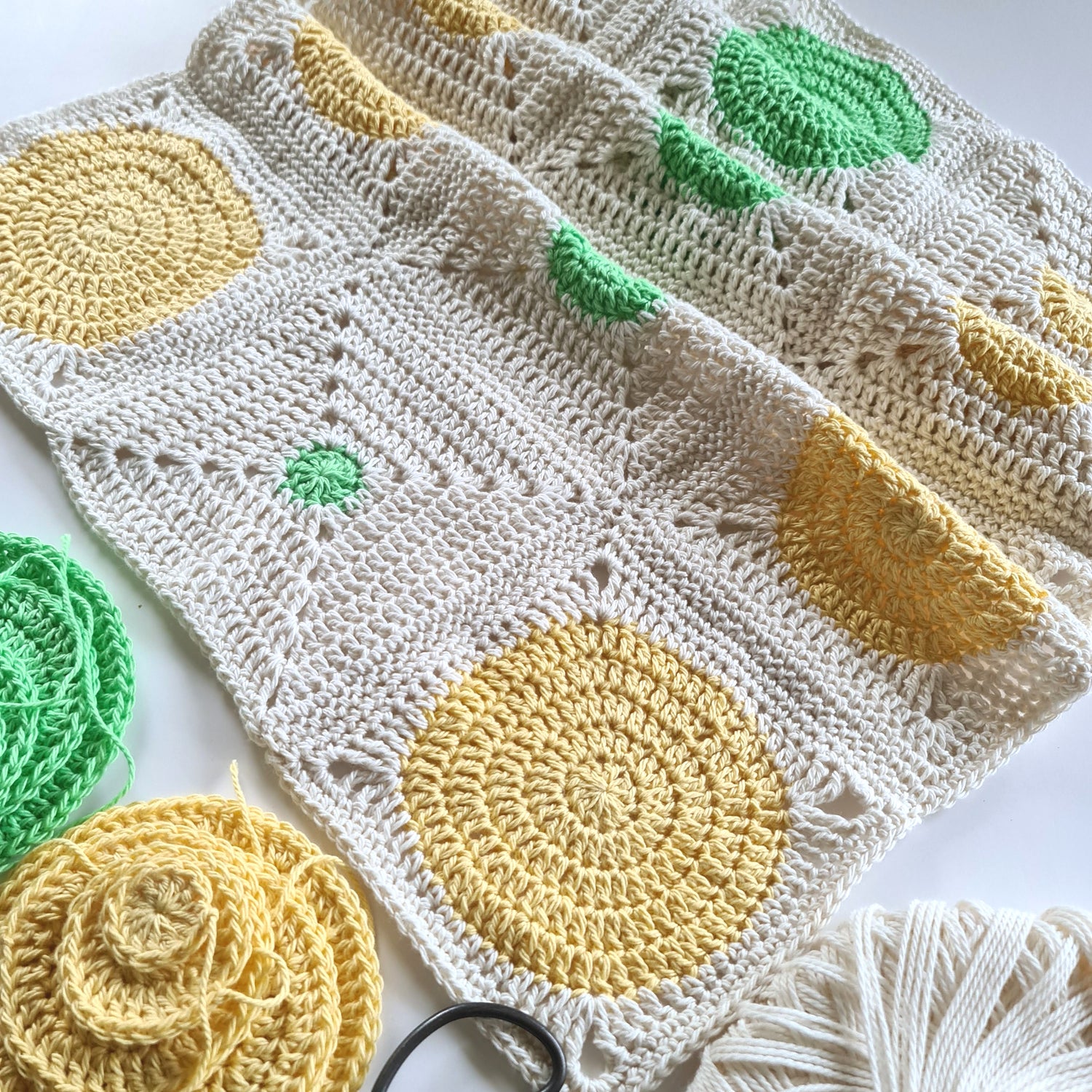 Pale yellow and bright green granny squares stitched in partially finished rows with loose circles waiting to become granny squares.